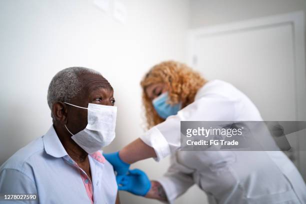 nurse applying vaccine on patient's arm using face mask - pneumonia patient stock pictures, royalty-free photos & images