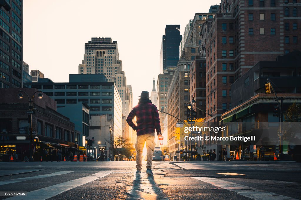 Man with paper coffee cup standing in the midst of the road, New York City