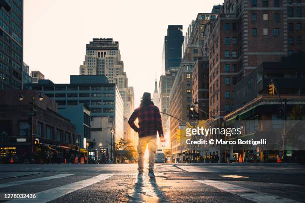 man with paper coffee cup standing in the midst of the road, new york city - straat stockfoto's en -beelden