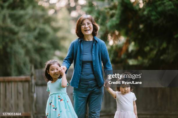 grandmother walking hand in hand with her granddaughters - korean people stock pictures, royalty-free photos & images