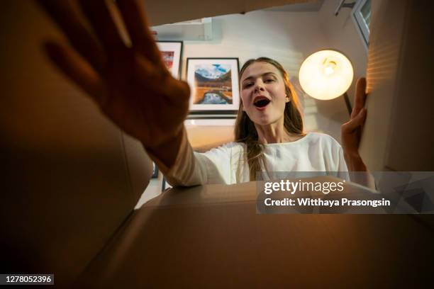 pretty young happy woman opening a carton box - geschenk auspacken stock-fotos und bilder