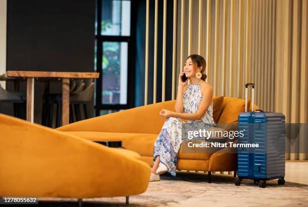 young tourist women on phone call by sitting on sofa at hotel lounge , entrance hall. - bangkok airport stock pictures, royalty-free photos & images