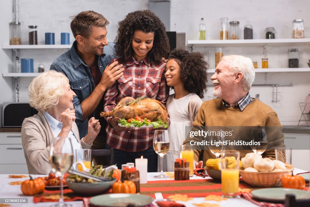 Selective focus of african american woman holding turkey near family during thanksgiving celebration