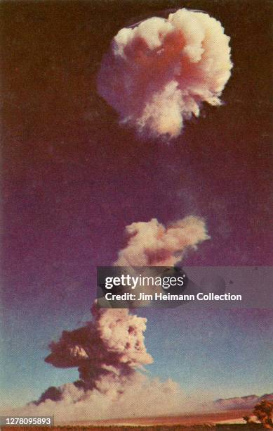 Photographic postcard shows an atomic cloud dissipating over an atomic detonation area, circa 1952.