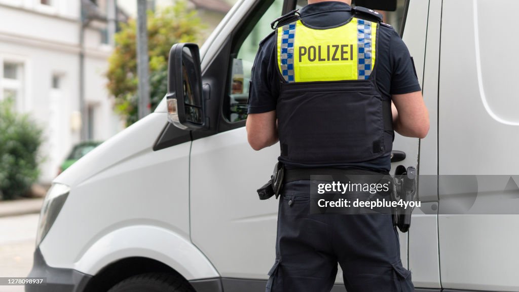 El policía controla una furgoneta blanca, en algún lugar de Hamburgo, Alemania