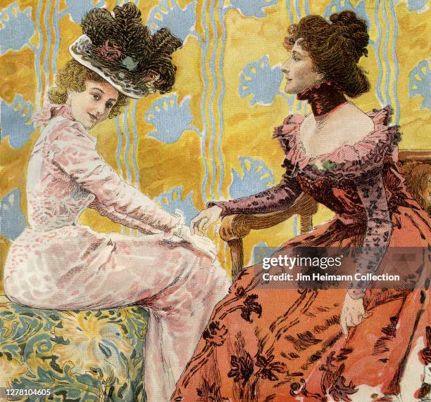 Two fashionable women in floral dresses sit in opposing chairs, possibly for a portrait, circa 1900.