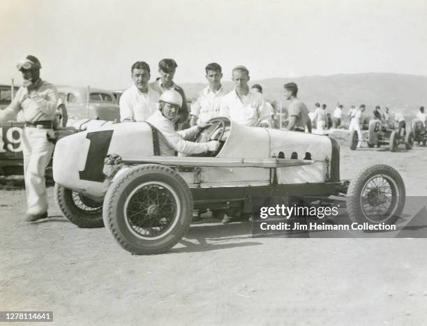 Group of men gather around a race car with a large number "1" painted on the side, circa 1939.