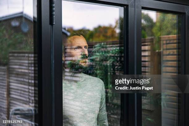 man looking through window - quarantäne stock-fotos und bilder