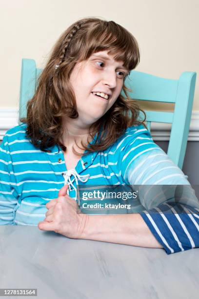 disabled and beautiful young adult smiles to herself after successfully completing her aba therapy at home - autismus stock pictures, royalty-free photos & images