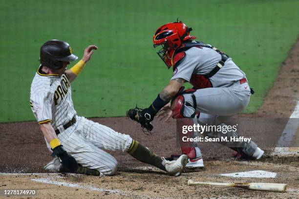 Jake Cronenworth of the San Diego Padres scores a run as Yadier Molina of the St. Louis Cardinals misses the ball during the seventh inning of Game...