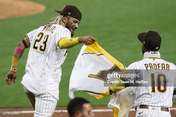 Fernando Tatis Jr. #23 and Jurickson Profar of the San Diego Padres run onto the field with a Padres flag following a series win against the St....