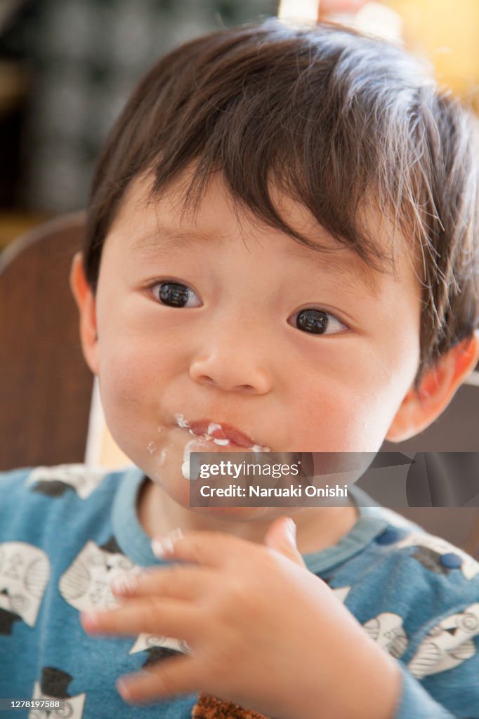 A one-year-old child who fills his mouth with yogurt