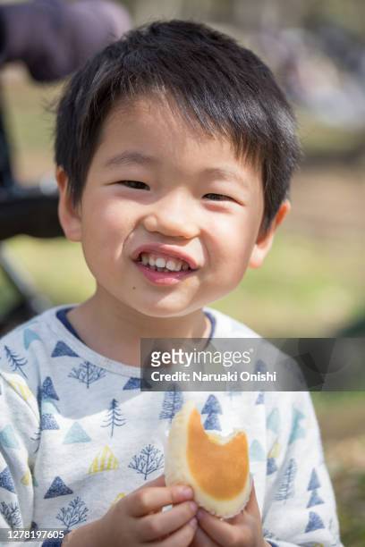 a boy eating sweet bread deliciously - östasiatiskt ursprung bildbanksfoton och bilder
