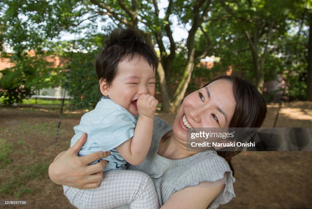 A baby hugged by a young mother and smiling