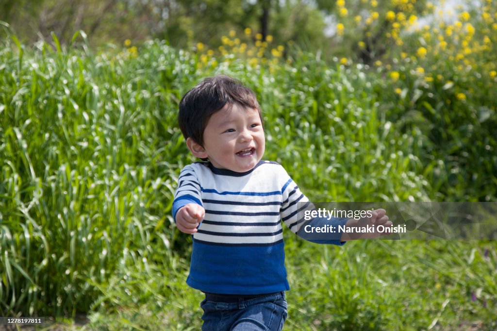 A one-year-old child running around a rape field