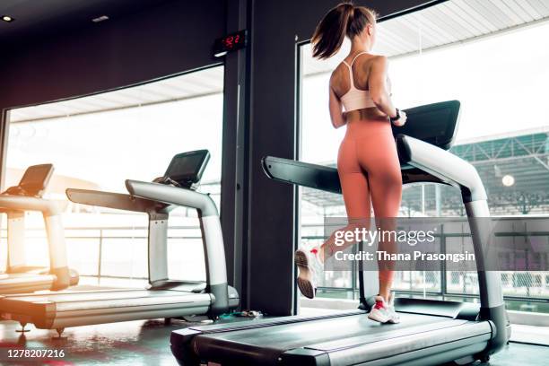 young woman jogging on a treadmill in a gym. - トレッドミル　女性 ストックフォトと画像