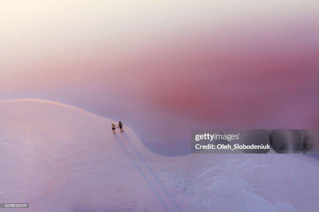 Scenic aerial view of couple walking on  pink salt lake