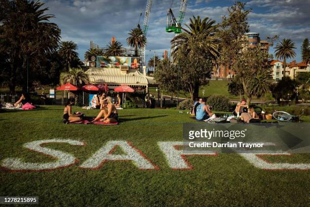 People enjoy the sun at St Kilda beach while social distancing on October 03, 2020 in Melbourne, Australia. Coronavirus restrictions eased slightly...
