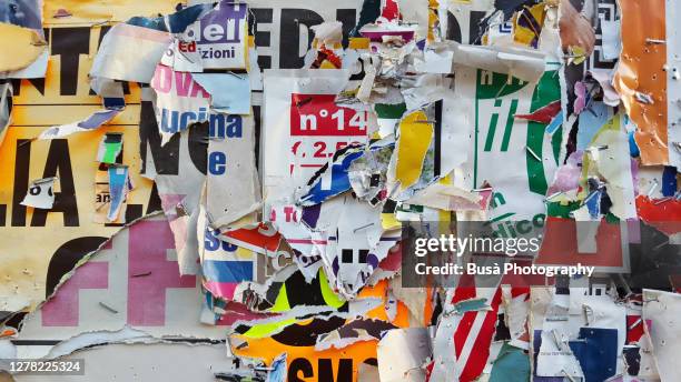 scratched layers of posters and placards on a street wall - word stock-fotos und bilder