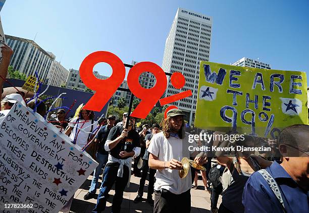 Protesters hold signs as they march to Los Angeles City Hall during the "Occupy Los Angeles" demonstration in solidarity with the ongoing "Occupy...