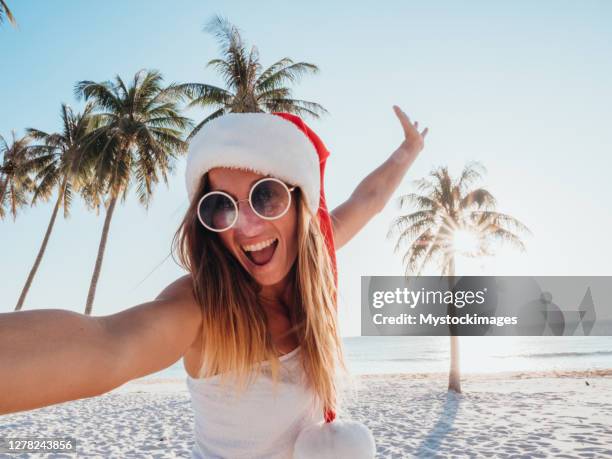 woman takes selfie on tropical beach at christmas - christmas palm tree stock pictures, royalty-free photos & images