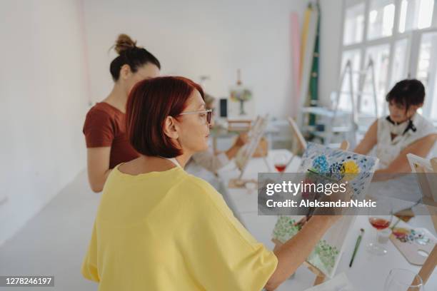 mature woman painting in art class - female friendship painting stock pictures, royalty-free photos & images