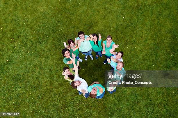 people standing in a circle on grass - medium group of people stock pictures, royalty-free photos & images