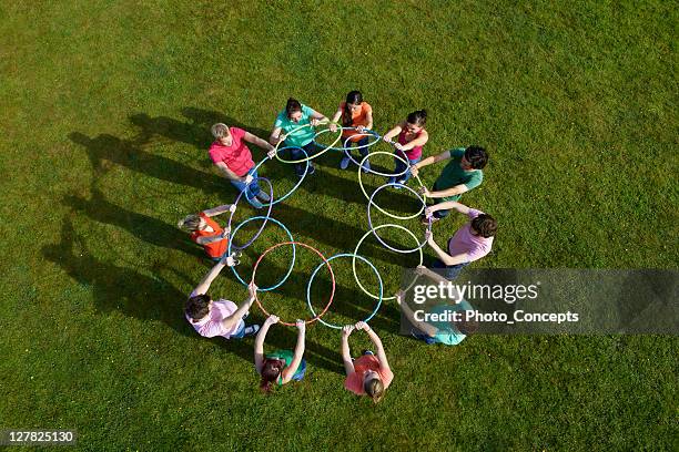 people holding hula hoops in circle - teambuilding stockfoto's en -beelden