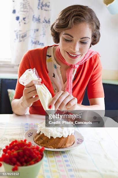 woman icing a cake in kitchen - ideal wife stock pictures, royalty-free photos & images