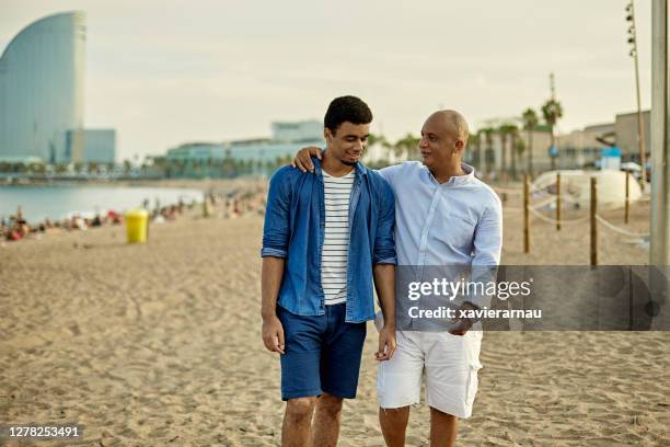 vader en zoon die en op strand barceloneta lopen - barceloneta stockfoto's en -beelden