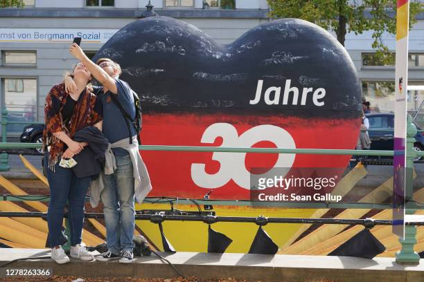 Couple, who said they did not mind being photographed, shoot a selfie in front of a giant heart painted in the colors of the German flag with the...
