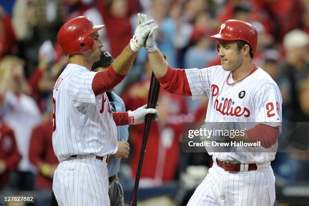 Chase Utley of the Philadelphia Phillies is congratulated by Raul Ibanez after scoring on a hit by Shane Victorino in the fourth inning of Game One...