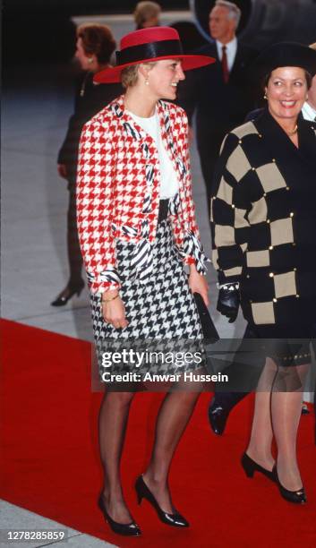 Diana, Princess of Wales, wearing a red and black houndstooth suit designed by Moschino and a red hat with black netting designed by Philip...