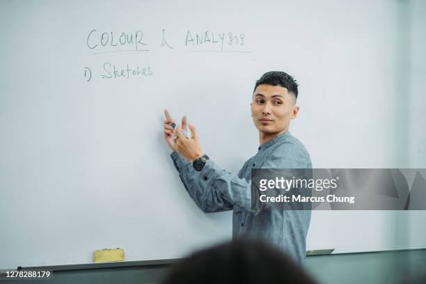 asian malay smiling male teacher giving lectures to his student at college classroom - lecturer whiteboard stock pictures, royalty-free photos & images