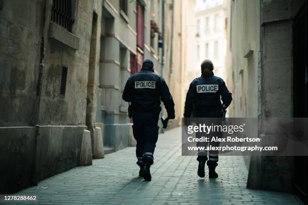 two french police officers patrol a paris alleyway - frankreich stock-fotos und bilder