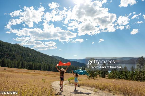 mädchen laufen mit ihren handtüchern an den strand - okanagan valley stock-fotos und bilder