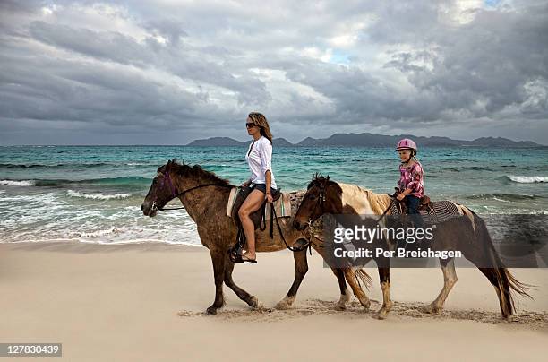 mother and daughter riding horses on a beach - anguilla photos et images de collection