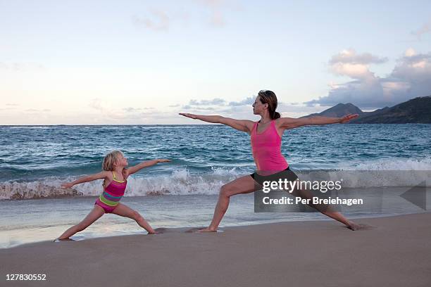 mother and daughter doing yoga on the beach - saint kitts and nevis stock pictures, royalty-free photos & images