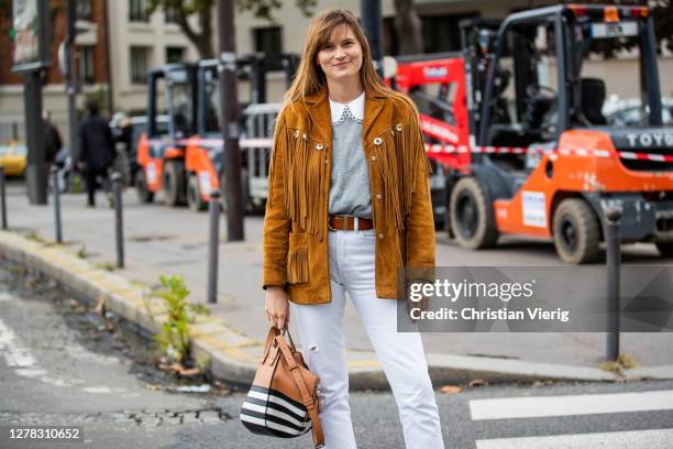 Guest is seen wearing brown jacket with fringes, Loewe bag, white pants outside Hermes during Paris Fashion Week - Womenswear Spring Summer 2021 :...