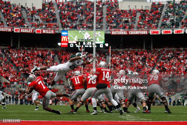 Denicos Allen of the Michigan State Spartans leaps over Jordan Hall of the Ohio State Buckeyes on his way to sacking Joe Bauserman of the Ohio State...