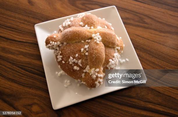 pan de muerto on a white plate on a wood table - pan de muerto stockfoto's en -beelden