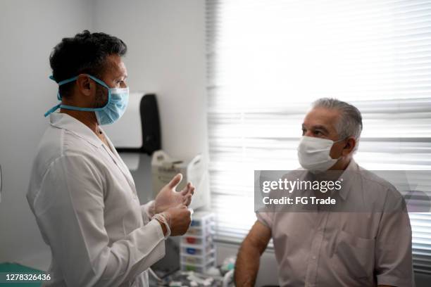 patient in a medical consult wearing face mask - 50 year old male patient stock pictures, royalty-free photos & images