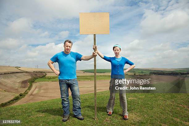 couple holding hill top protest - placard stockfoto's en -beelden