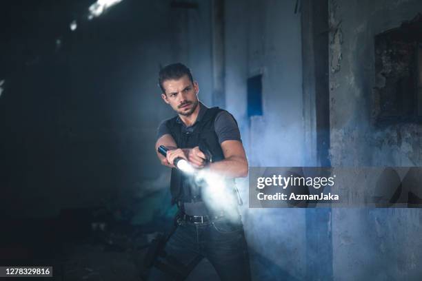 alert police officer pointing flashlight and pistol into fog - police flashlight stock pictures, royalty-free photos & images