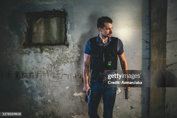police officer standing in run-down urban setting at night - bullet proof vest stock pictures, royalty-free photos & images