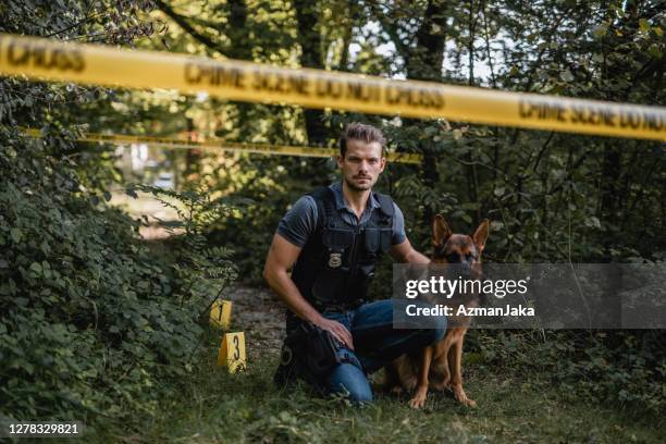 grave giovane ufficiale maschile e cane poliziotto sulla scena del crimine - cane poliziotto foto e immagini stock