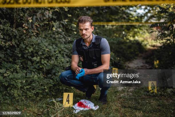 ernstige jonge politieagent die chirurgische handschoenen opdoet - crime scene stockfoto's en -beelden