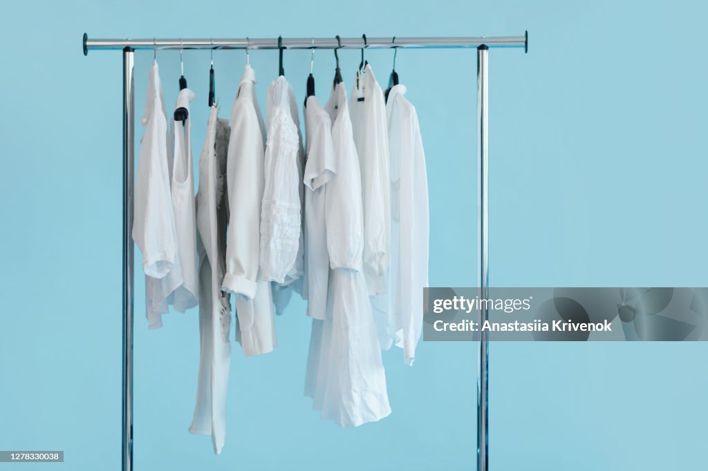 Close-Up of white clothes hanging on rack on blue background.