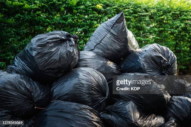 concepts save the world and environmental issues, garbage bags stacking storage against green trees backgrounds. waste management - garbage bag stock pictures, royalty-free photos & images