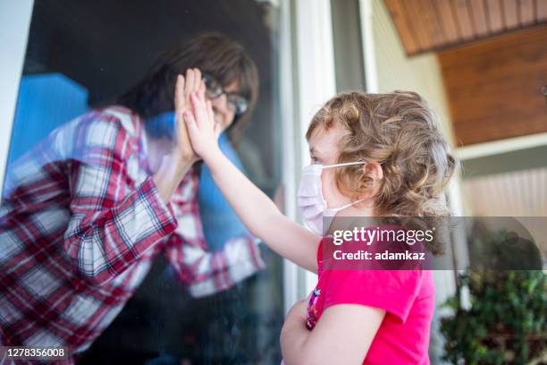 grandma greeting granddaughter through window social distancing - covid visit stock pictures, royalty-free photos & images